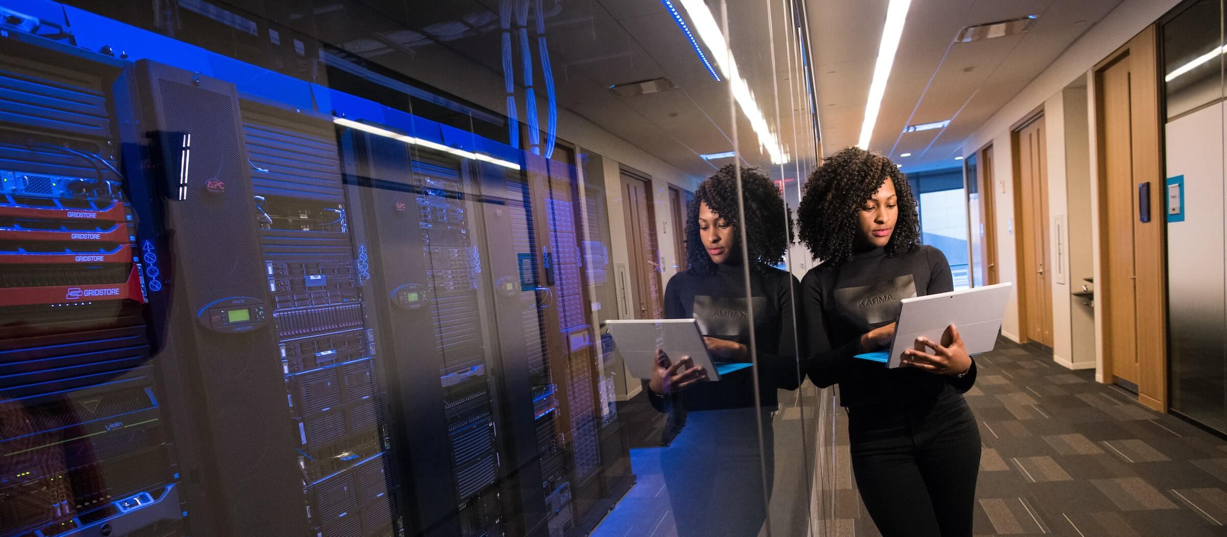 A woman on her laptop leaning on a security server room